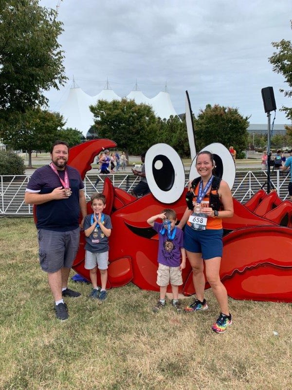 The whole family showing off their medals in front of a giant grab prop.